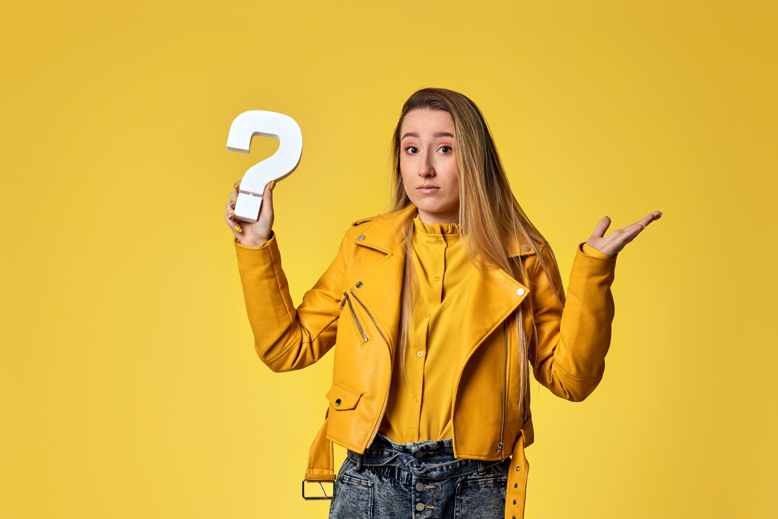 beautiful woman in leather jacket with question mark on yellow background